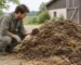 Eine Person hockt neben einem Haufen dunklen Stallmists mit Stroh und betrachtet eine Handvoll Material.